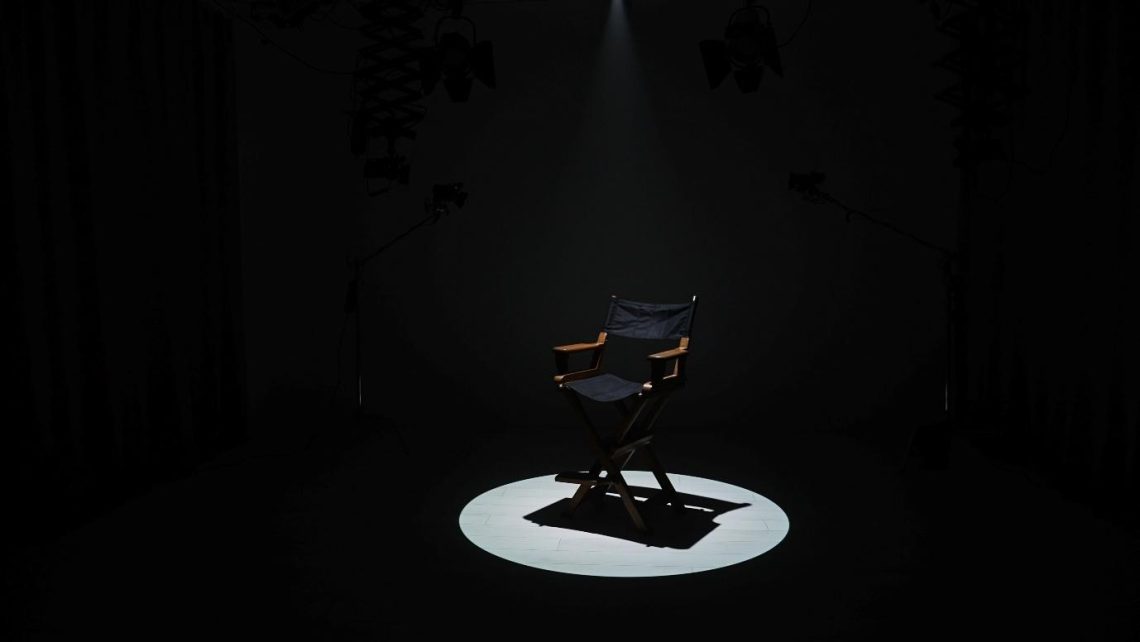 An empty circle of wooden chairs placed in a quiet room, symbolizing the absence of wartime sexual violence survivors with direct reference to the comfort women and others whose stories remain untold