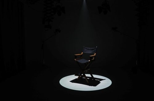 An empty circle of wooden chairs placed in a quiet room, symbolizing the absence of wartime sexual violence survivors with direct reference to the comfort women and others whose stories remain untold